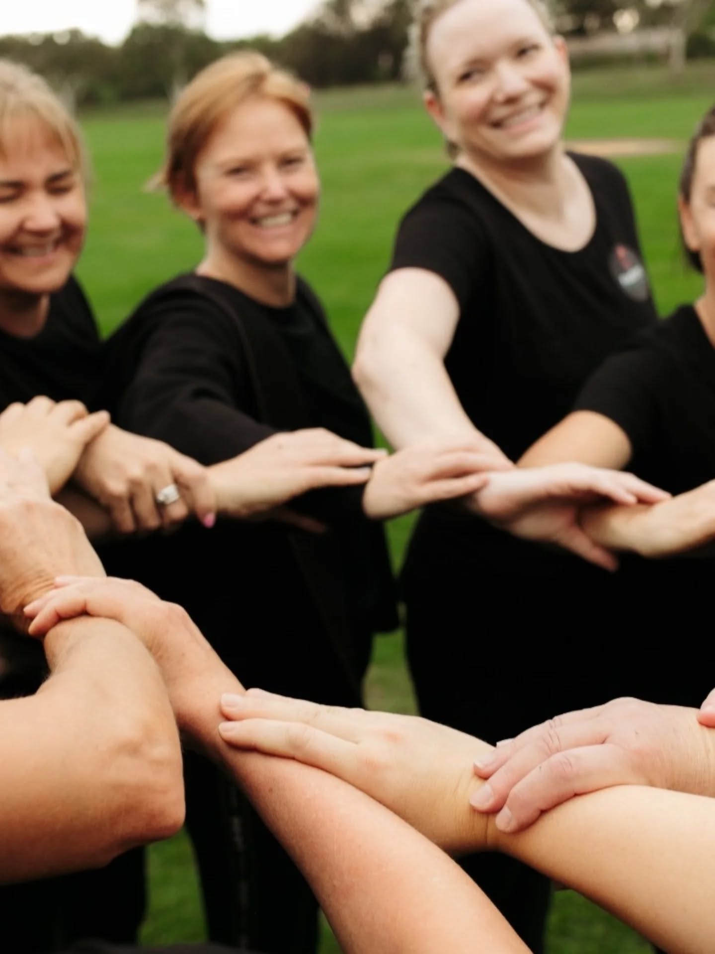 Women joining hands after a group fitness session in Canberra